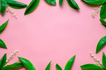little bouquets of lilly of the valley as a floral frame with copy space. Flat lay with pink background. 