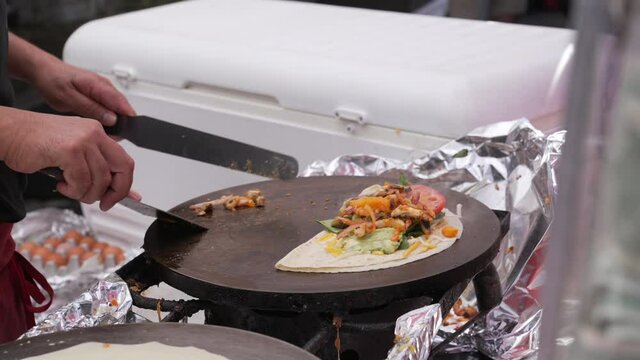 This close up video shows professional chef making and folding a delicious crepe meal.