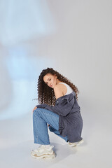 Portrait of a young woman in jeans, white top and shirt, slim toned body. Fashion studio shot
