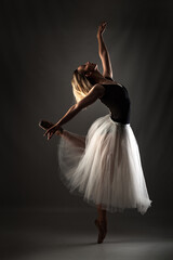 Fototapeta na wymiar ballerina with a white dress and black top posing on gray background.
