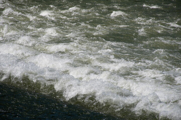 Close-up of the agitated water of a stretch of the Isar River with a fast current in Munich,...