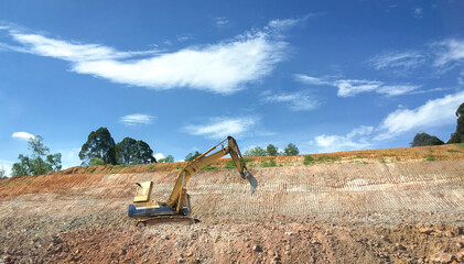 Excavator on a hill slope, involved in earthmoving construction project or road works.