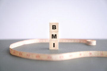 BMI word on wood cubes with measuring tape on table. Copy space.