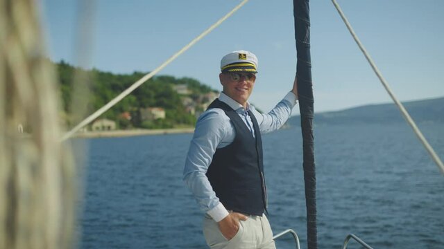Cheerful sailor captain standing at bow of boat. Sailing along coast. Summer vacation at sea, sailing and travelling concept.