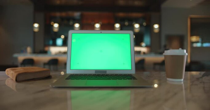 Laptop compuer with green chroma key mock up screen in office cafeteria. Close up shot of digital device display set up for work in cafe - technology concept 4k footage