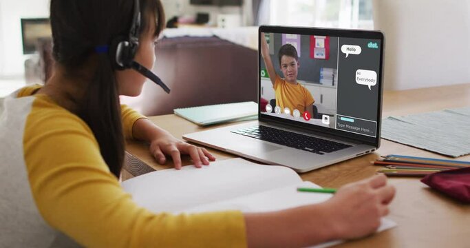 Schoolgirl using laptop for online lesson at home, with boy raising hand and webchat on screen