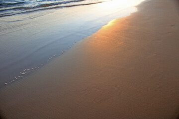 Reflexes at sunset on the wet sand of the beach