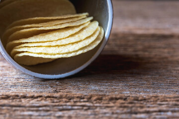 Slice of potato chips crisps in paper tube box on wooden planks.