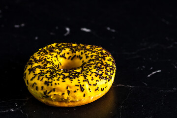 Yellow donut with sprinkles on black background