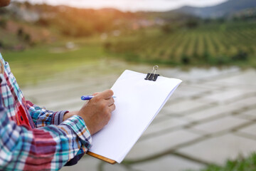 farmer stands on the field and keeps a record of planning work for the day.