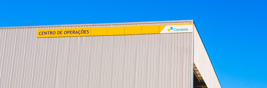 Correios - Empresa Brasileira de Correios e Tel&eacute;grafos, empresa brasileira. Fachada com logo dos correios e c&eacute;u azul de fundo. 