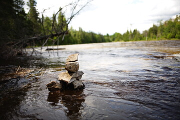 A small inukshuk along the side of a river in rural Ontario, Canada. A traditional symbol of the...