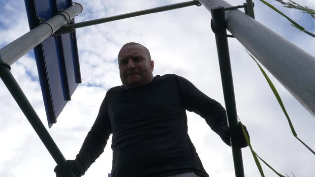 Active Guy Doing Dip Bar Workout With Self-made Bars On Road Signs. Strengthening Tricep Muscles Outdoor During Covid-19 Pandemic. low angle