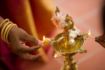 Woman lighting a traditional brass oil lamp during a Hindu wedding celebration