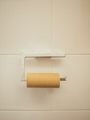 Empty toilet paper roll on holder against tiled bathroom wall
