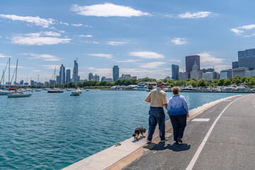 A senior couple enjoys a walk with their dog in Chicago, along the Lakefront Trail, on a lovely...