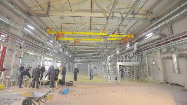Builders create a self-leveling floor. The builders do the work inside. Creation of a self-leveling floor inside the workshop at the factory