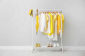 Rack with bright stylish clothes, shoes and accessories near grey wall indoors