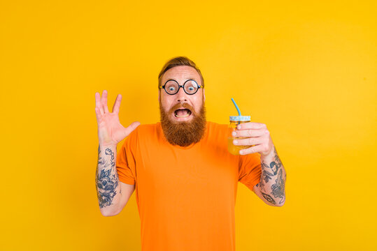 Nerd afraid man with glasses drinks a fruit juice