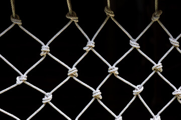 White net with dark background showing repeated pattern of weaving and knots