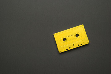 A bright yellow magnetic cassette on a black background. Flat lay.