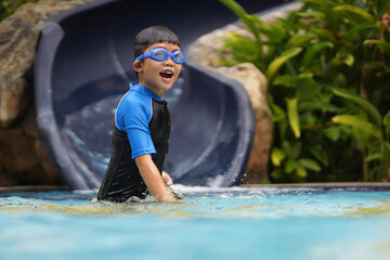 Happy little Asian boy having fun in the swimming pool. Summer outdoor water activity for kids.