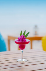 dragon fruit smoothie with fruit slices on sand and beach background. selective focus (close up view)