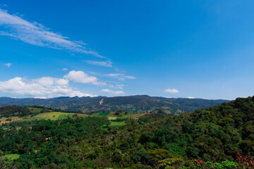 Fototapeta na wymiar Landscape of mountains, country houses and crops with a blue sky and some clouds in Colombia.