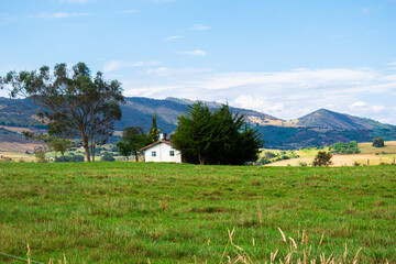 country house with green trees, located in the middle of a meadow with green pastures and with a mountainous background.