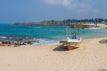 Fototapeta na wymiar Fishing boat on the ocean shore on a sunny day. Ambalangoda, Sri Lanka