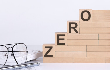 wooden cubes with letters ZERO on the white table with keyboard and glasses
