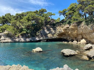 Turquoise sea lagoon at summer sunny day. Beautiful rocky beach among pine trees Mediterranean...