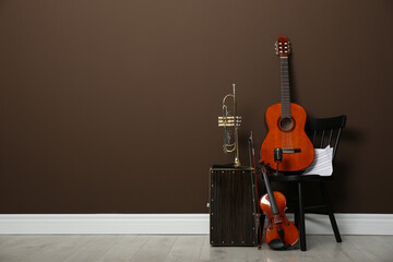 Set of different musical instruments near brown wall indoors, space for text