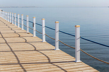 Naklejka premium Travel. Pier on the sea. View at the sea from the wooden pier with posts and ropes with sparkling sea water