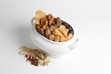 Chinese traditional luxury cuisine buddha jump over the wall with seafood abalone, sea cucumber, shark's fin, scallop and meat in hot herbal soup clay pot in white gold background asian menu for new y