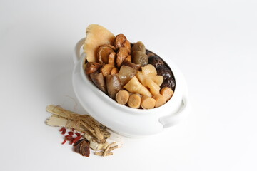 Chinese traditional luxury cuisine buddha jump over the wall with seafood abalone, sea cucumber, shark's fin, scallop and meat in hot herbal soup clay pot in white gold background asian menu for new y