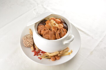 Chinese traditional luxury cuisine buddha jump over the wall with seafood abalone, sea cucumber, shark's fin, scallop and meat in hot herbal soup clay pot in white gold background asian menu for new y
