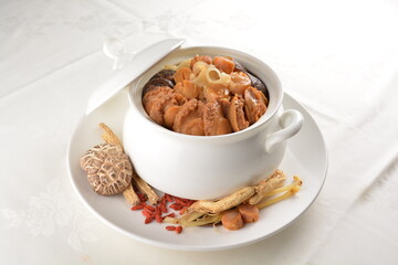 Chinese traditional luxury cuisine buddha jump over the wall with seafood abalone, sea cucumber, shark's fin, scallop and meat in hot herbal soup clay pot in white gold background asian menu for new y