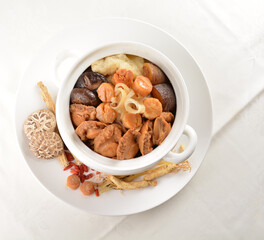 Chinese traditional luxury cuisine buddha jump over the wall with seafood abalone, sea cucumber, shark's fin, scallop and meat in hot herbal soup clay pot in white gold background asian menu for new y