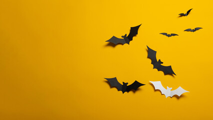 Halloween decorations concept. Black paper bats on orange background. Banner, copy space.