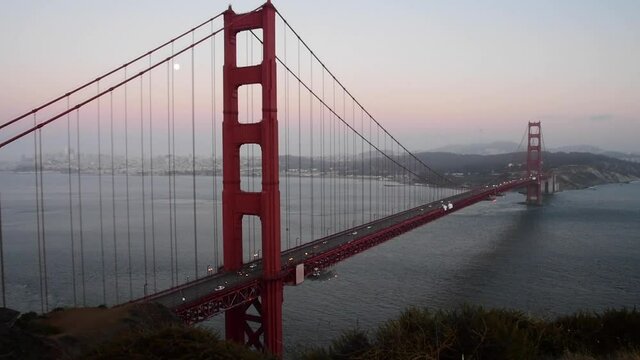 View of the Golden Gate Bridge at sunset. The ocean can be seen as well as San Francisco on the other side of the red bridge 