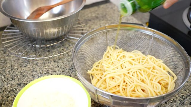 close up hands of people pouring olive oll in pasta
