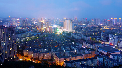Pretty night scene of a city with tall buildings, brightly lit. High-angle shot