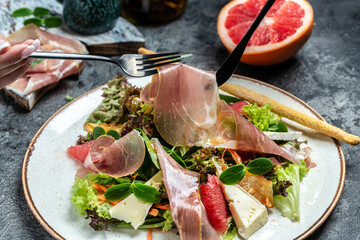Prosciutto crudo ham salad with brie camembert cheese and grapefruit, salad mix. Restaurant menu,...