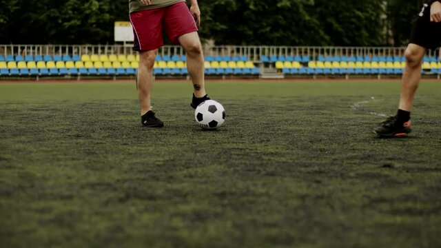 The football team training in the city stadium and works out the game moments. Close-up of athletes legs