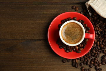 Cup of tasty coffee and beans on wooden table, flat lay. Space for text