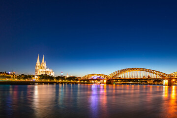 In Cologne, Germany, the river is shining brightly with the light at night, a beautiful bridge. Long shot