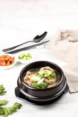 Gori Gomtang (Sokkori Gomtang) or Korean Beef Oxtail Stew  Soup, Served in the Black Korean Bowl with Kimchi and Sliced Green Onion