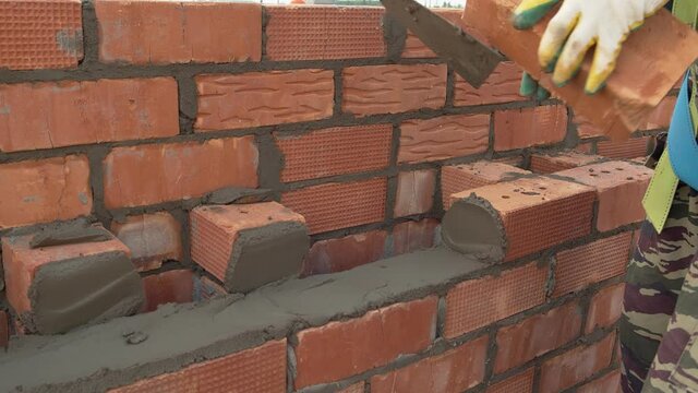 The worker lays the brick on a pre-prepared layer of cement mortar. Construction site, materials for construction. Slow motion. High quality. 4k footage.