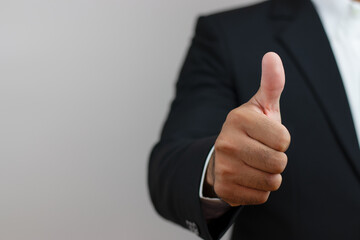 Business man thumbs up to indicate success, likes,encourages, wins - close-up.